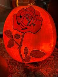 A pumpkin with a rose carved on it
AI-generated content may be incorrect.